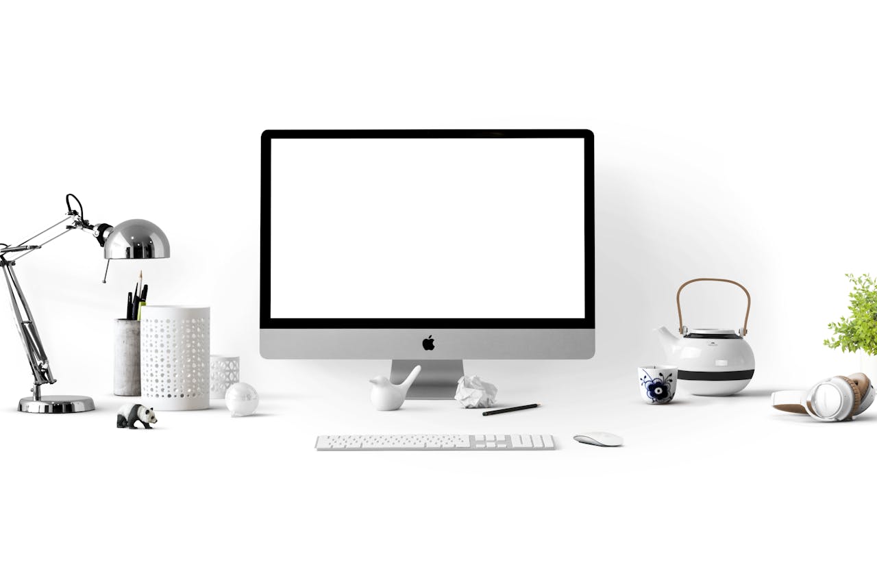 Minimalist office desk with an iMac, lamp, and stationary, perfect for tech backgrounds.